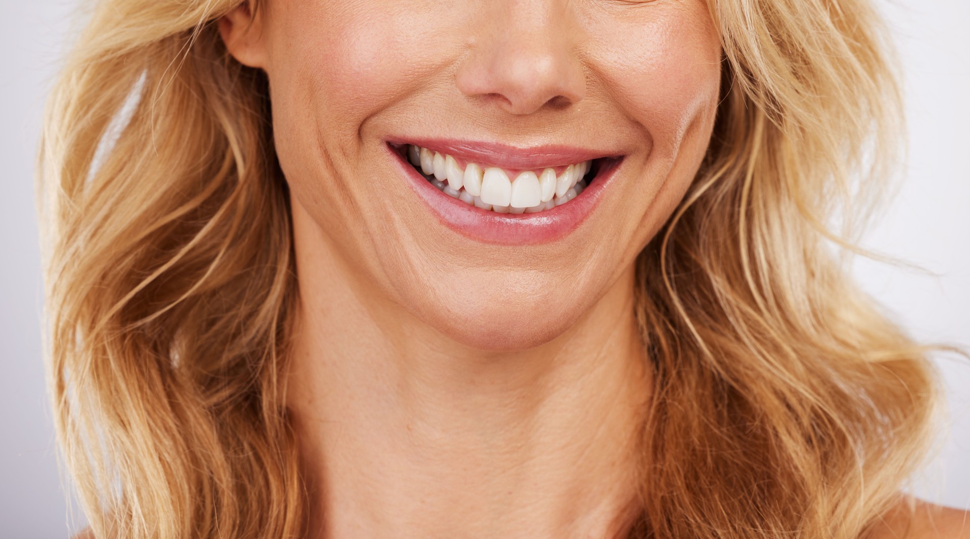 Closeup, smile and woman mouth in studio for dental, hygiene or teeth whitening on grey background. Oral, zoom and cleaning for lady satisfied with bleaching, braces or porcelain veneers results